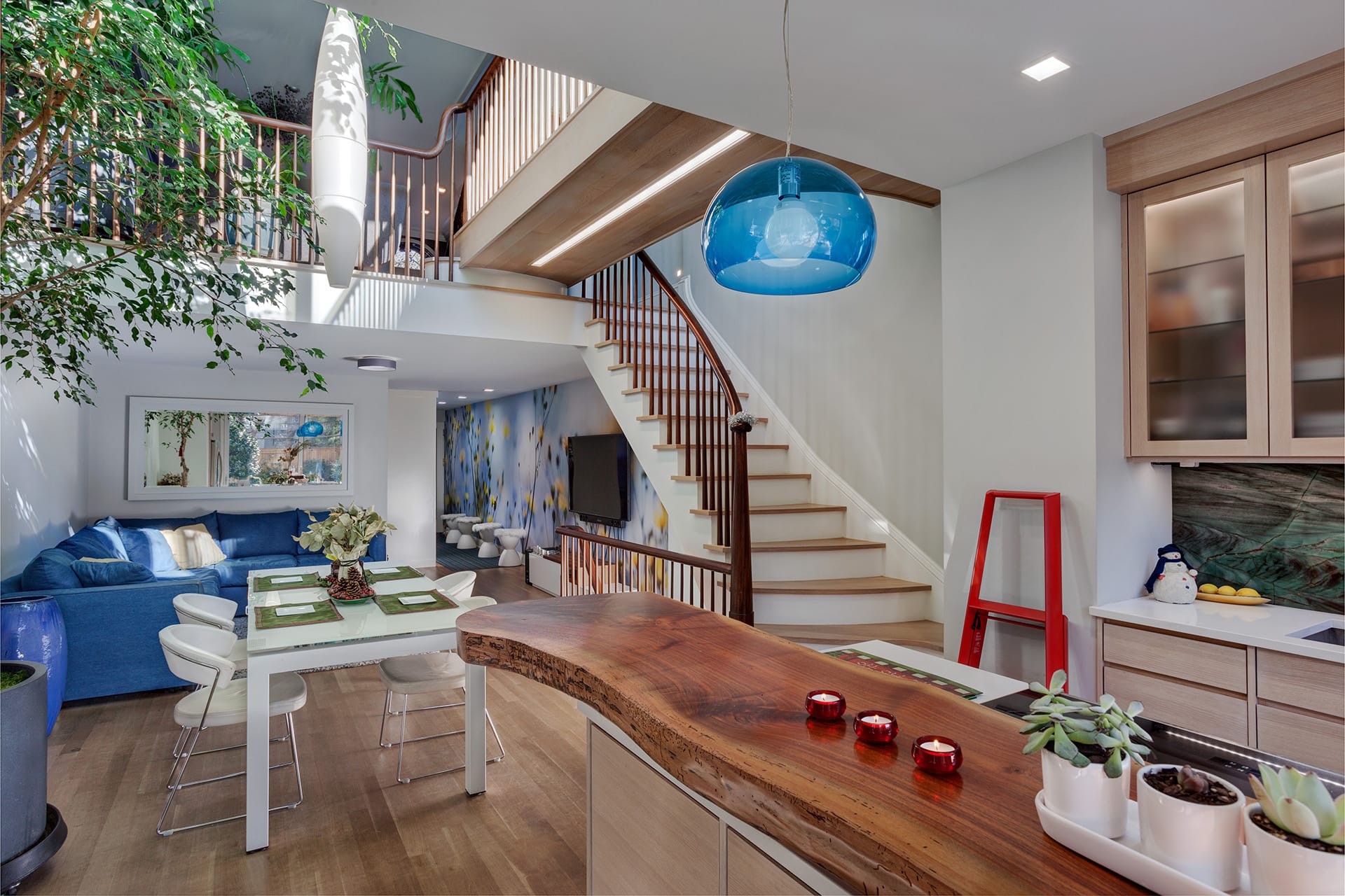 View of dining room and double height space in a Carroll Gardens home with the kitchen island in the foreground.